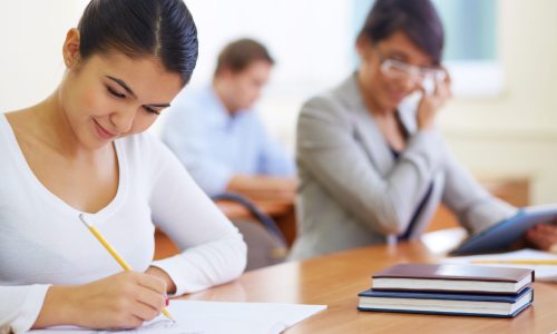 Portrait of pretty girl sitting in college library and making notes