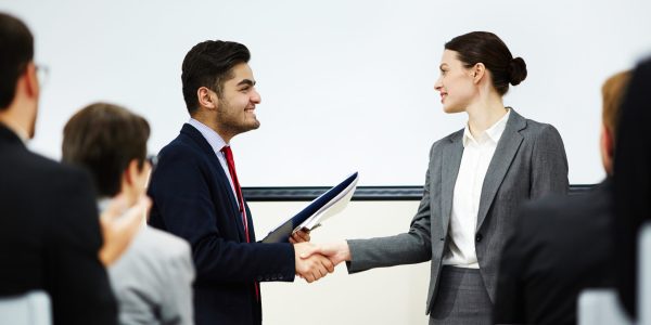 Coach congratulating one of business course attendants on graduation event